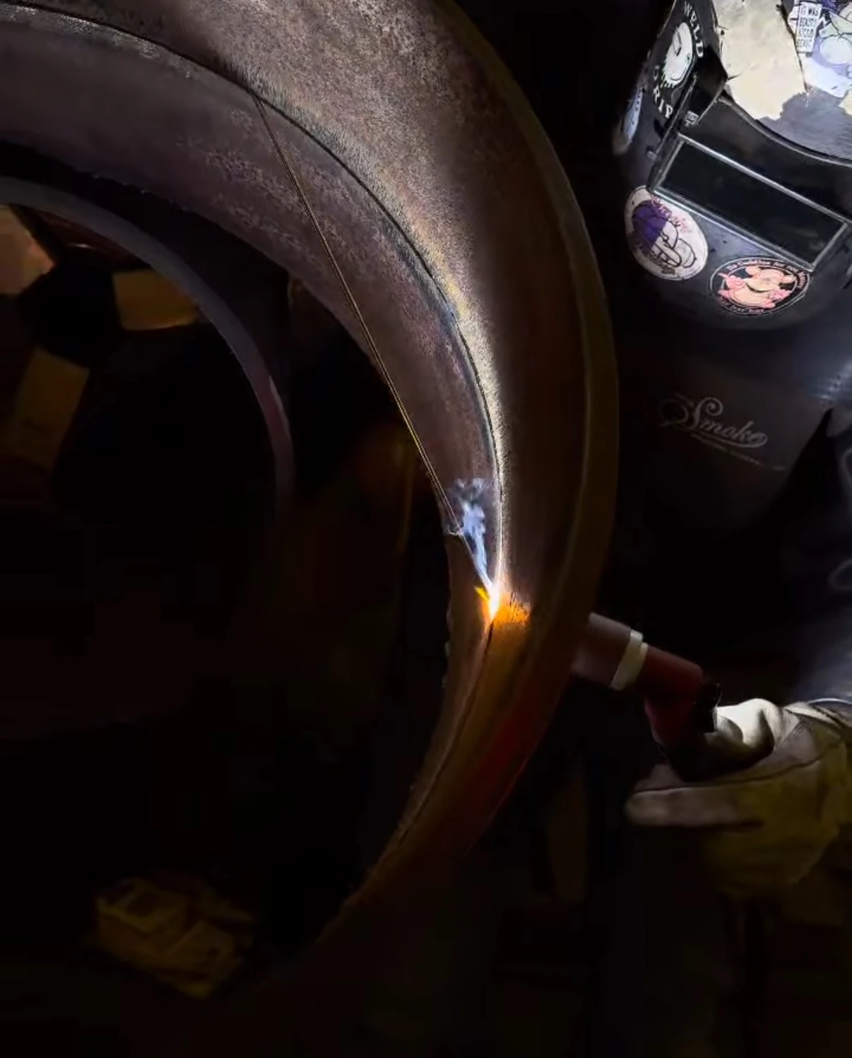 Travis Field welding at a pipe opening with the arc visible near the joint