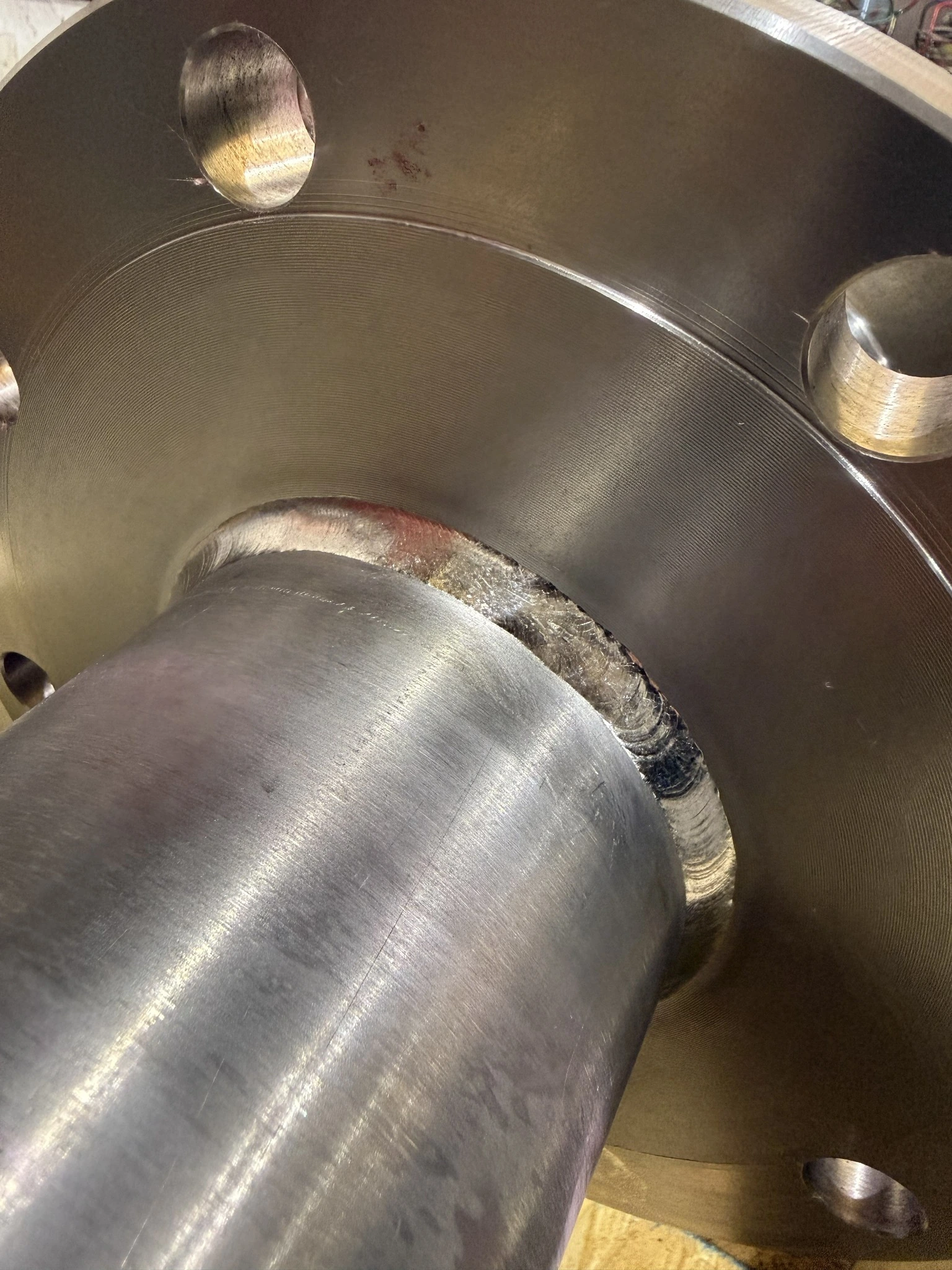 Close-up of a completed circumferential weld beside a bolted flange