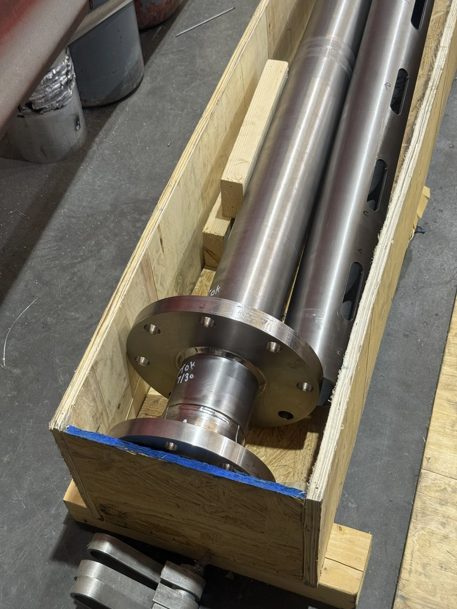 Full-length flanged pipe assembly resting inside a wooden shipping crate