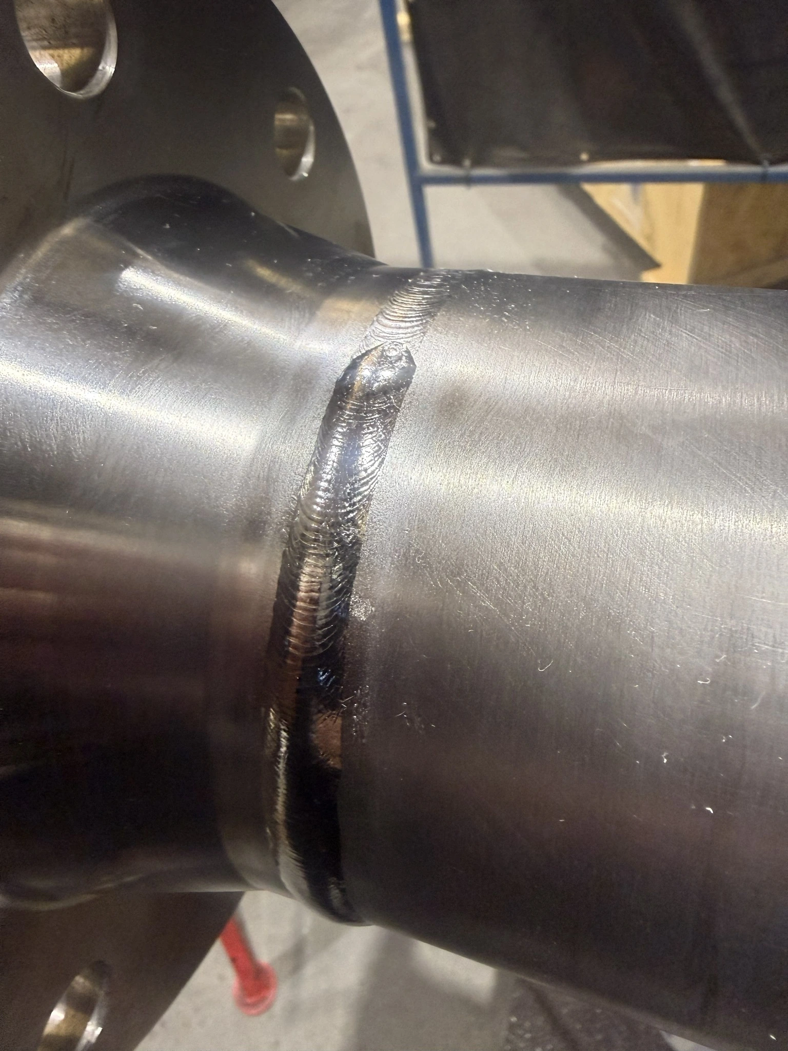 Close view of a pipe-to-flange-neck butt weld on a polished assembly