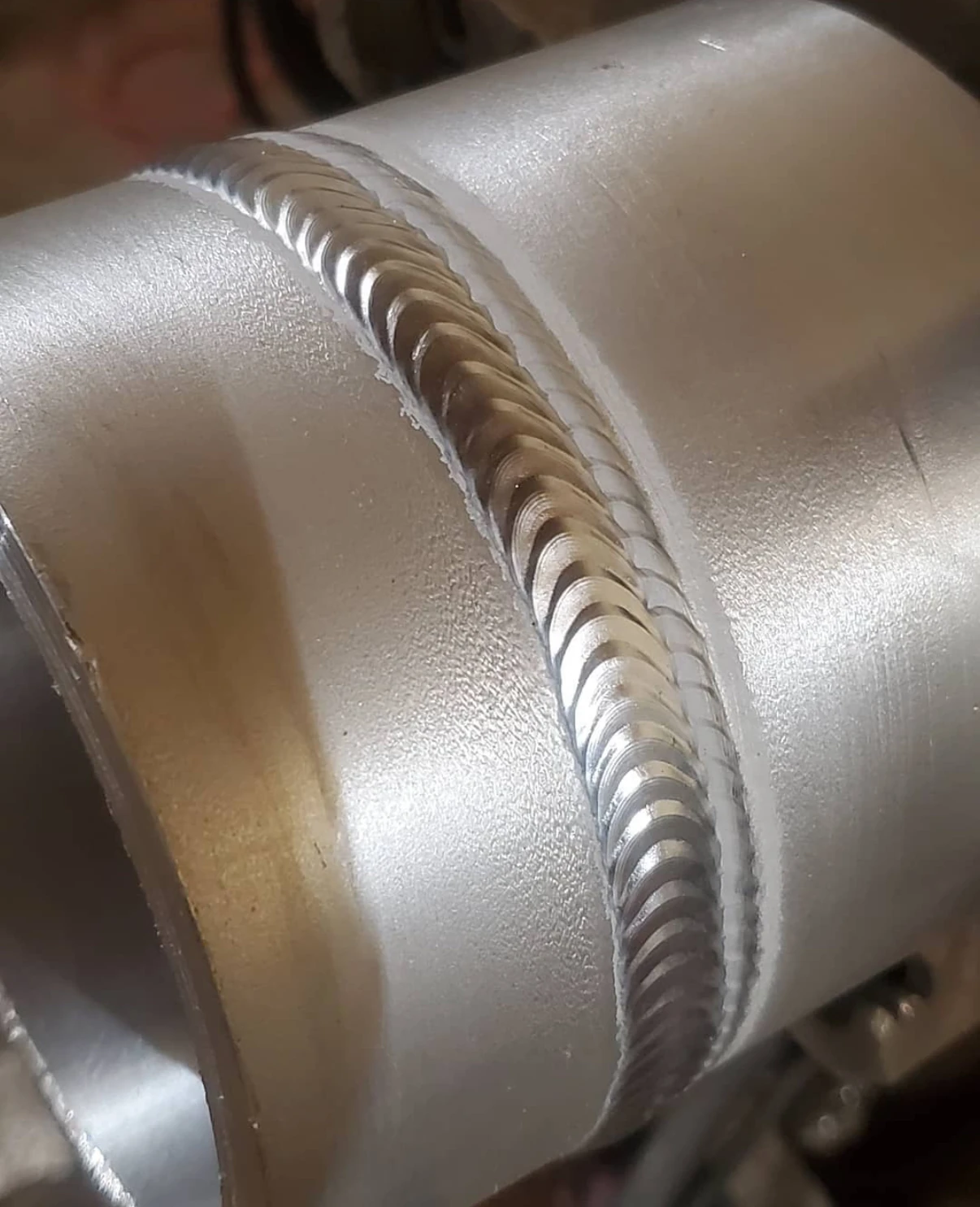 Close view of a circumferential pipe weld showing the bead profile and tie-ins