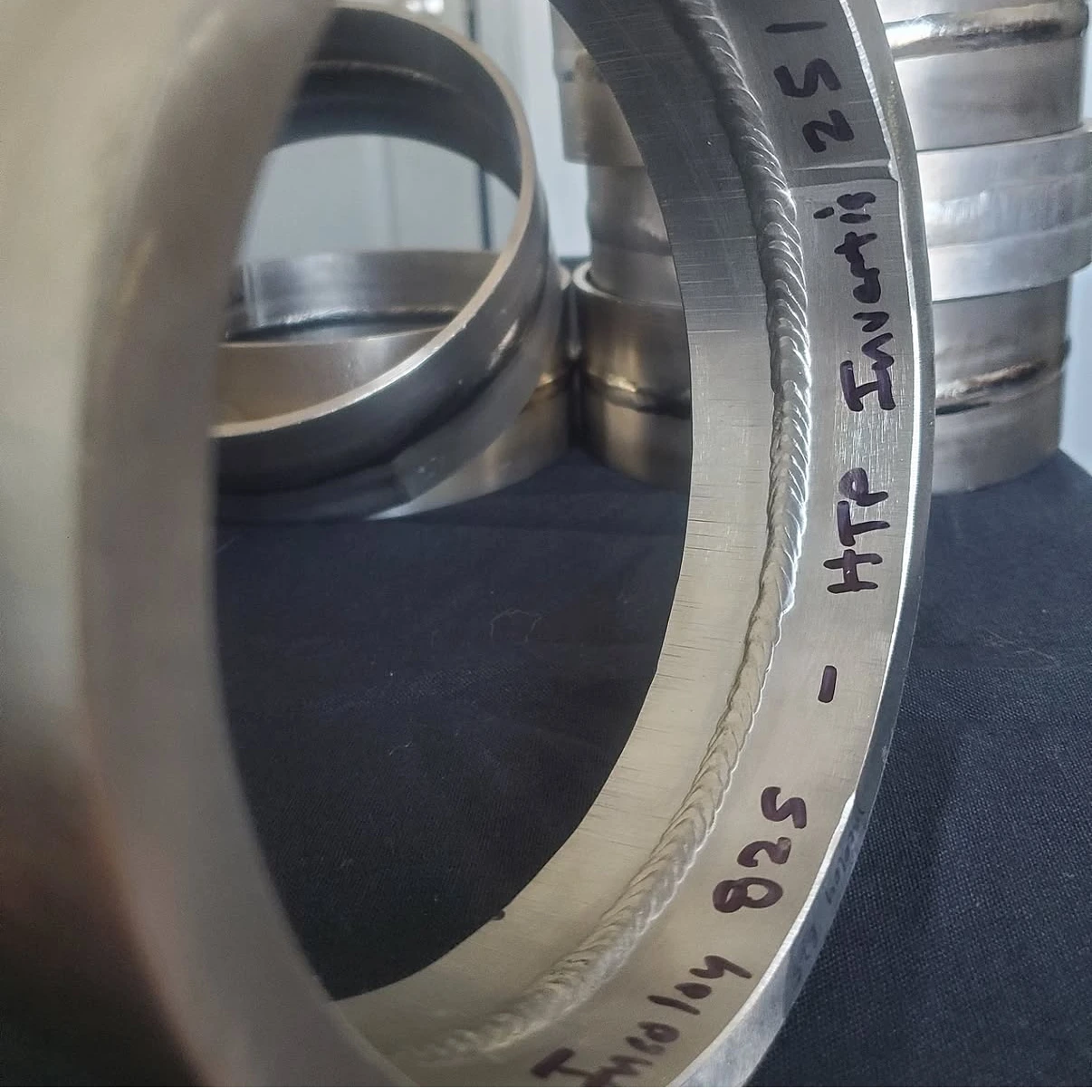 Sectioned Incoloy 825 pipe weld sample with the material name marked beside the weld