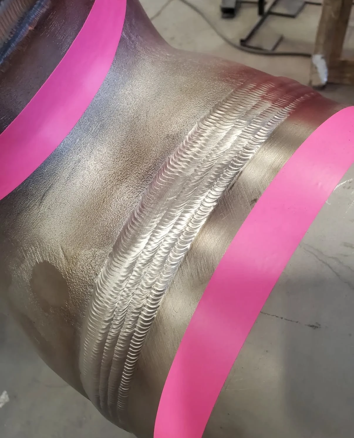 Detailed view of a multi-pass pipe weld between marked bands