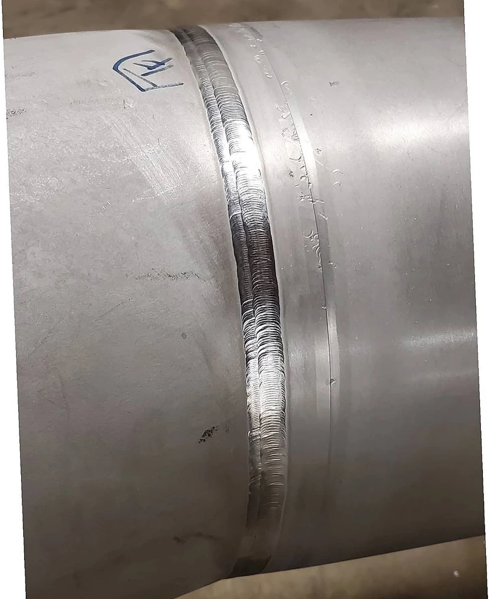 Close view of a completed pipe weld beside a TF marking