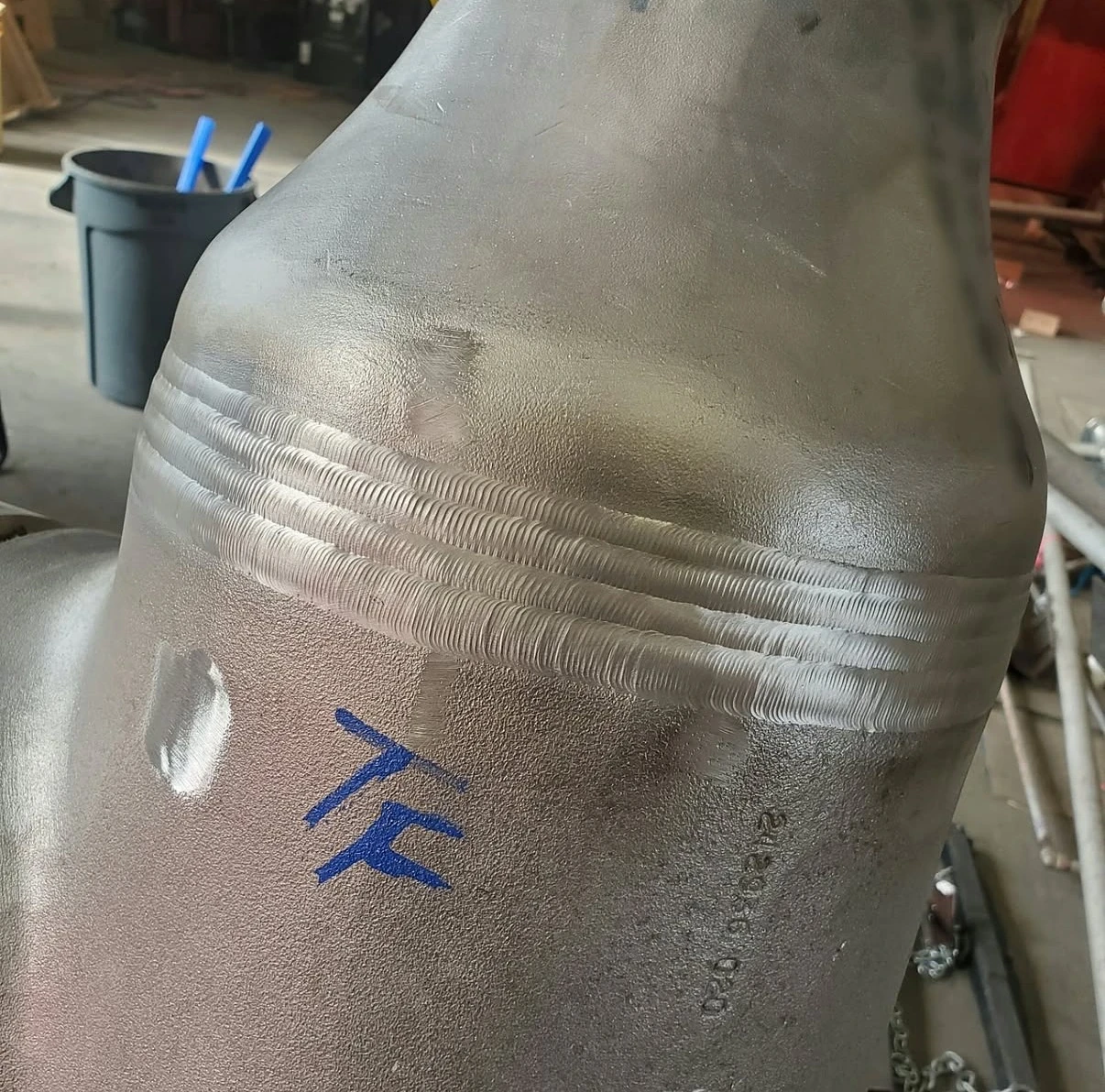 Completed weld on a pipe reducer with a TF marking beside the joint