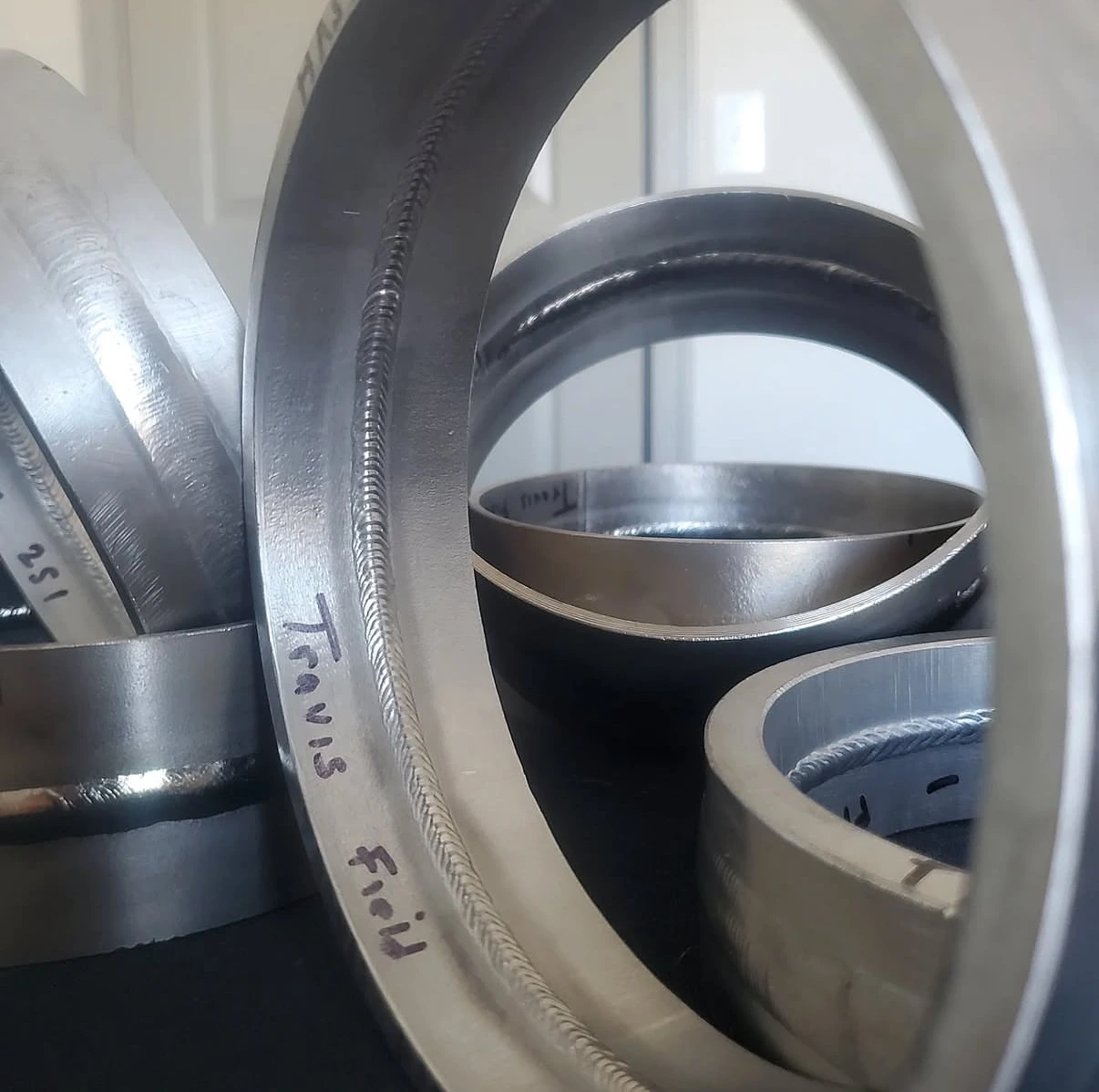 Sectioned weld ring marked Travis Field, with other welded samples behind it