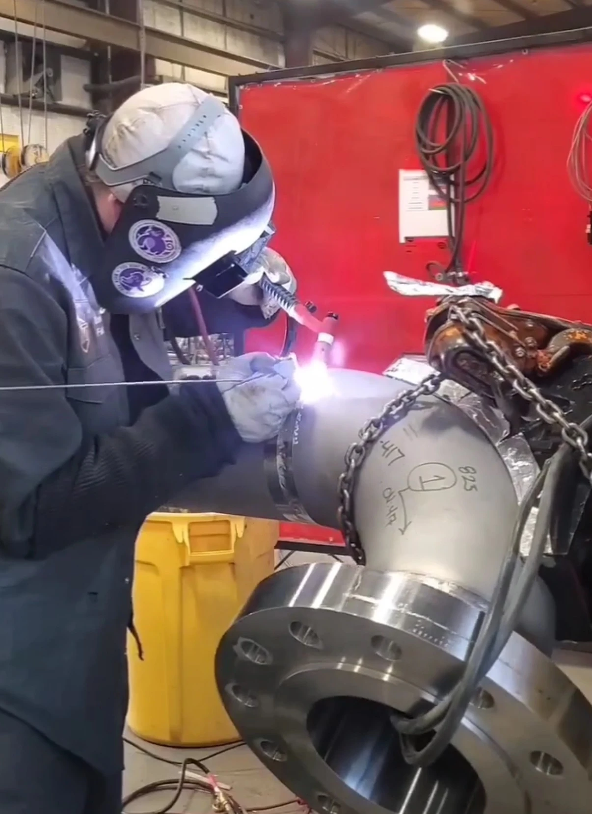 Travis Field TIG welding a pipe elbow assembly with a large flange in the foreground