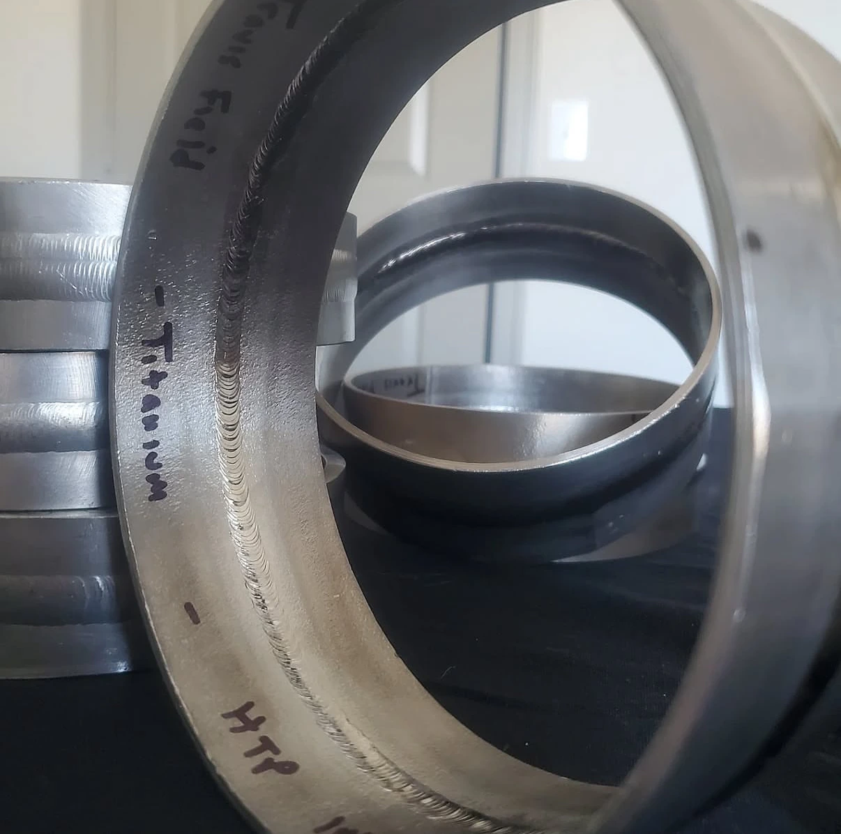 Sectioned pipe weld sample marked Titanium and Travis Field, with the internal weld visible
